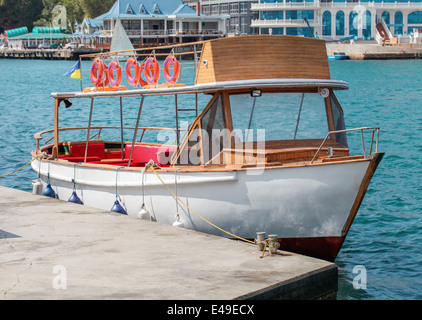 Small motor boat by dock on the blue sea Stock Photo