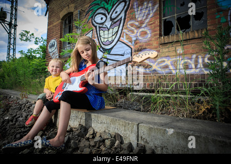 outdoor portrait of a little boy and teenage girl with a guitar Stock Photo