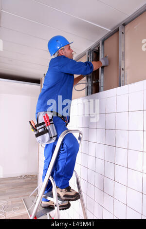 Construction worker panelling wall Stock Photo