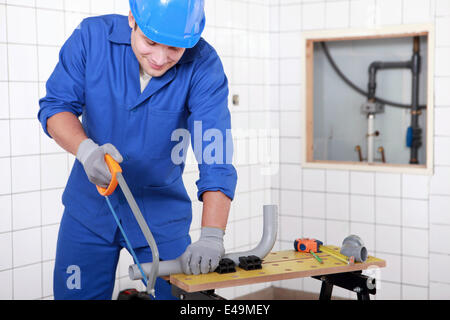 Plumber sawing plastic pipe Stock Photo