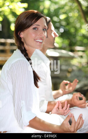 Couple meditating in garden Stock Photo