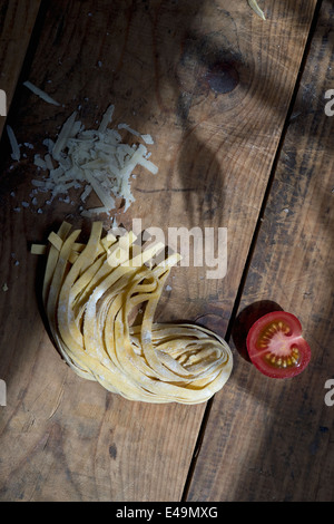 Fresh unwrought tagliatelle, tomatoe and shadow of a fork Stock Photo