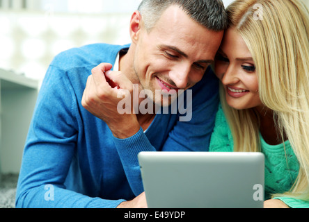 Young couple lying on the carpet and using tablet computer together Stock Photo
