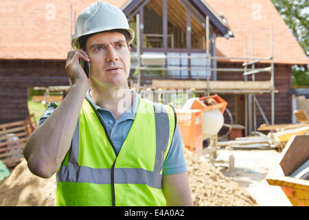 Construction Worker On Building Site Using Mobile Phone Stock Photo