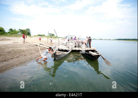 Car and tractor on a village ferry made from two wooden boats and wooden platform, Brahmaputra river, Majuli, Assam, India Stock Photo