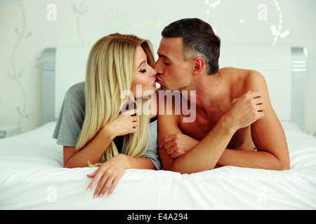 Loving young couple lying on the bed and kissing Stock Photo