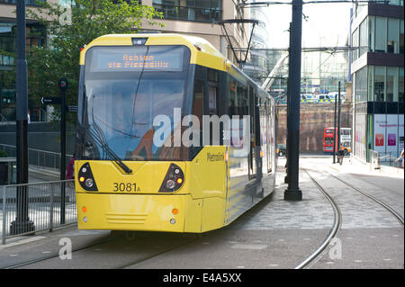 Manchester, UK. 7th July, 2014. A Metrolink tram runs down a city centre street in Manchester towards Piccadilly station. The UK government has pledged £328 million towards improving the North West England's transport network, which includes 12 new Metrolink trams. Credit:  Russell Hart / Alamy Live News. Stock Photo