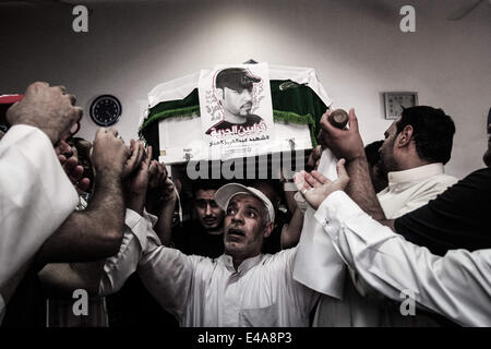 Sanabis, Bahrain. 6th July, 2014. Bahrain, Sanabis - Thousands attend the funeral of Abdul Aziz al-Abbaar in the village of Sanabis west of the capital Manama, Abdulaziz was hit in his head by a tear gas canister and birds bullets shot on February 23rd when he was taking a part in clashes with riot police and died from wounds on April 18th, Al-Abbar's body was in the morgue for 76 days because his family refused to sign the death certificate which ministry of interior said his death was because of brain damage © ZUMA Press, Inc./Alamy Live News Stock Photo