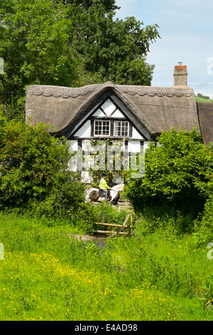 A horse rider and a thatched black and white cottage in the Village of Hopton Castle, South Shropshire, England. Stock Photo