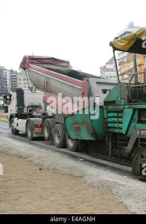 Truck dumping asphalt to running paving machine Stock Photo