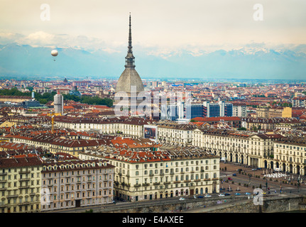 View of the city of Turin, Italy from the Convento Monte dei Cappuccini and looking across the Piazza Vittorio Veneto. On the left a hot-air balloon rises into the sky. Centre is the spire of the Mole Antonelliana. The Alps rise up in the background. Stock Photo