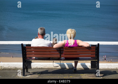 Mature couple sitting on bench overlooking Saltburn beach. Saltburn by the sea, North Yorkshire, England, UK Stock Photo