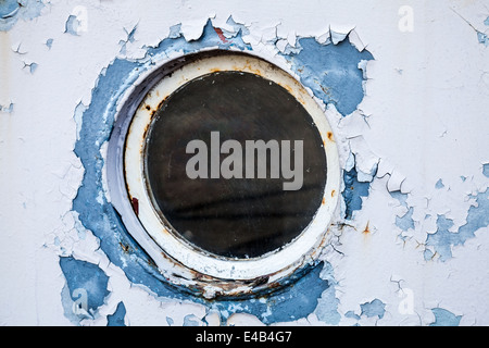 Round porthole in white and blue ship wall Stock Photo