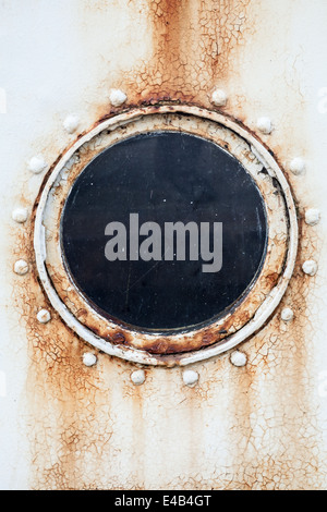 Round rusted porthole on white ship wall Stock Photo