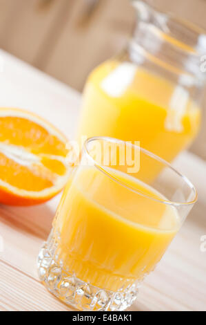 Glass and pitcher of juice on table. Stock Photo