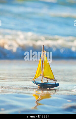 The little toy boat stands on sandy beach Stock Photo