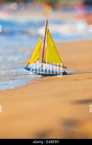 The little toy boat stands on sandy beach Stock Photo