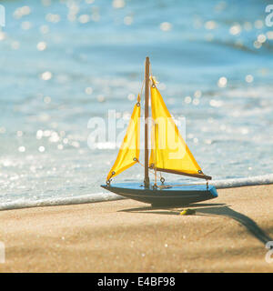 The little toy boat stands on sandy beach Stock Photo