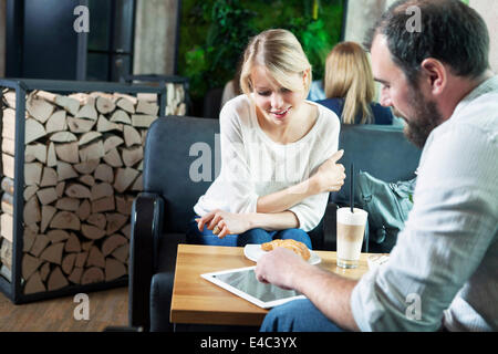 Couple dating in a cafe, man using digital tablet Stock Photo