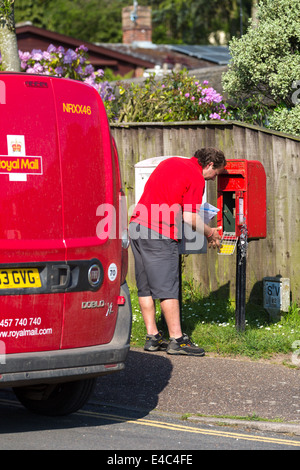 Postman emptying letter post box after collection of mail. Norfolk Broads England UK Stock Photo