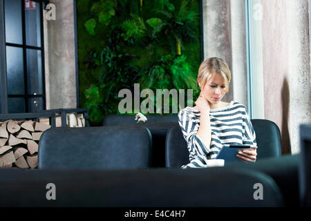 Mid adult woman using digital tablet in a cafe