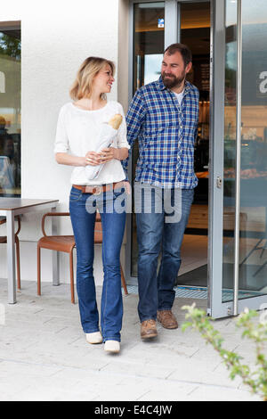 Couple leaving bakery, woman holding fresh bread in hands, Munich, Bavaria, Germany Stock Photo
