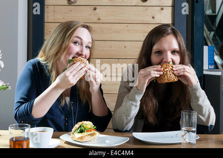 Two young women eating sandwiches in a cafe Stock Photo