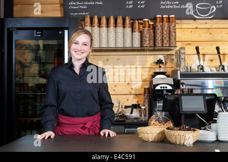 Shop assistant standing behind counter in coffee shop Stock Photo