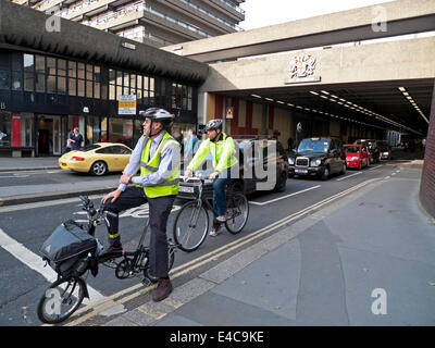 Businessmen men office workers commuters wearing helmets cycling home after work waiting on bikes for traffic lights Barbican London UK  KATHY DEWITT Stock Photo
