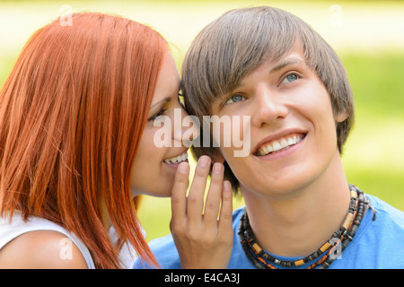 Teenage woman whispering to her boyfriend loving couple summer time Stock Photo