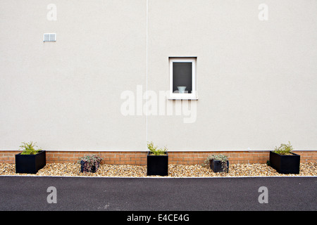 View of side wall to newly built home with decorative planters in a gravel bed Stock Photo