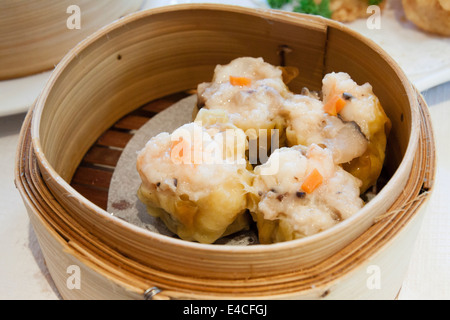 Siu mai/shumai Chinese steamed dumplings in a bamboo steamer,Chinese dim sum restaurant,  Soho, London, England, UK Stock Photo