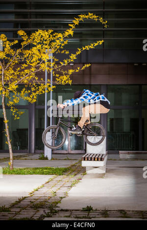 BMX biker performing a stunt on the sidewalk Stock Photo