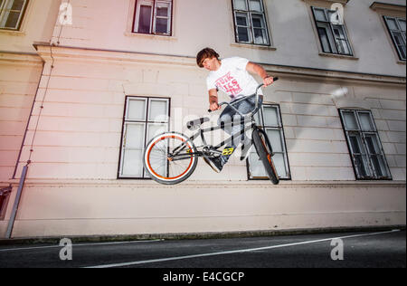 BMX biker performing a stunt in front of a house Stock Photo