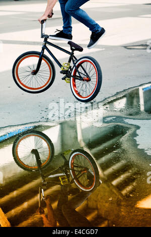 Reflections in a puddle of BMX biker performing a stunt Stock Photo