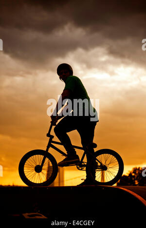 BMX biker with bike standing against sunset Stock Photo
