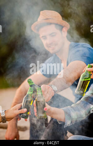 Group of young people toasting with beer by campfire, Osijek, Croatia Stock Photo