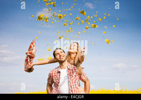 Young couple fooling around in colza field, Tuscany, Italy Stock Photo