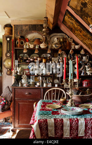 Old wooden dresser displaying 18th century teabowls, early Victorian lustreware and Staffordshire figures. A hand-sewn quilt is Stock Photo