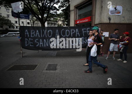 Belo Horizonte, Brazil. 8th July, 2014. Residents pass by a slogan protesting against the organization of the FIFA World Cup in Belo Horizonte, Brazil, on July 8, 2014. Credit:  Mauricio Valenzuela/Xinhua/Alamy Live News Stock Photo