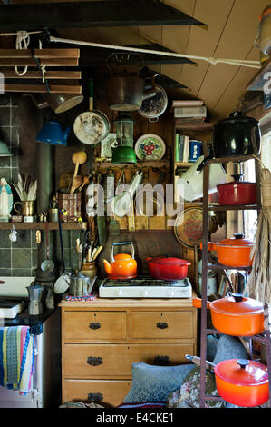 Le creuset pots on an iron rack in cluttered country kitchen with gas stove Stock Photo