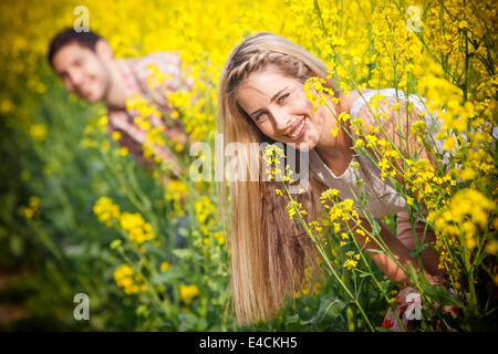 Young couple in colza field playing hide and seek, Tuscany, Italy Stock Photo