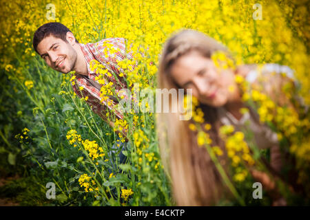 Young couple in colza field playing hide and seek, Tuscany, Italy Stock Photo