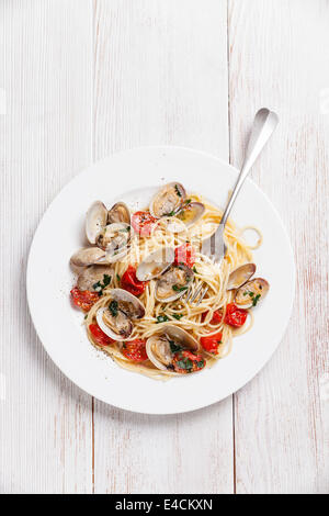 Seafood pasta with clams in tomato sauce Spaghetti Vongole on white wooden background Stock Photo