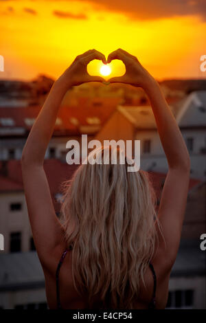 Young woman making a heart shape against sunset, Osijek, Croatia Stock Photo