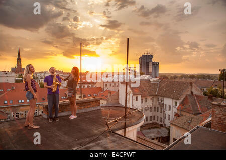 Man playing the saxophone on rooftop at sunset, Osijek, Croatia Stock Photo