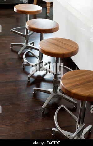 Set of four chrome bar stools with wooden seats Stock Photo