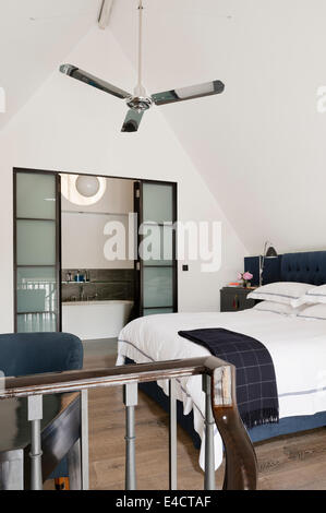 Silver ceiling fan in white bedroom with ensuite bathroom Stock Photo