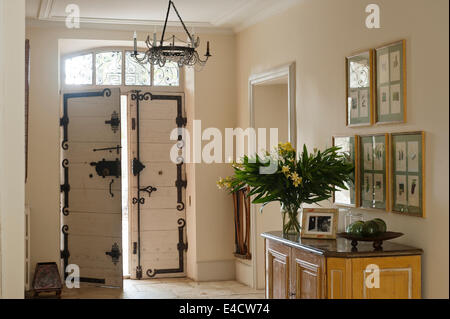 Old wooden door with black iron handle and hinges in hallway with stone flooring Stock Photo