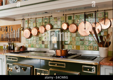 A range of copper pans hung above a semi-professional Molteni cooker in kitchen with decorative wall tiles Stock Photo